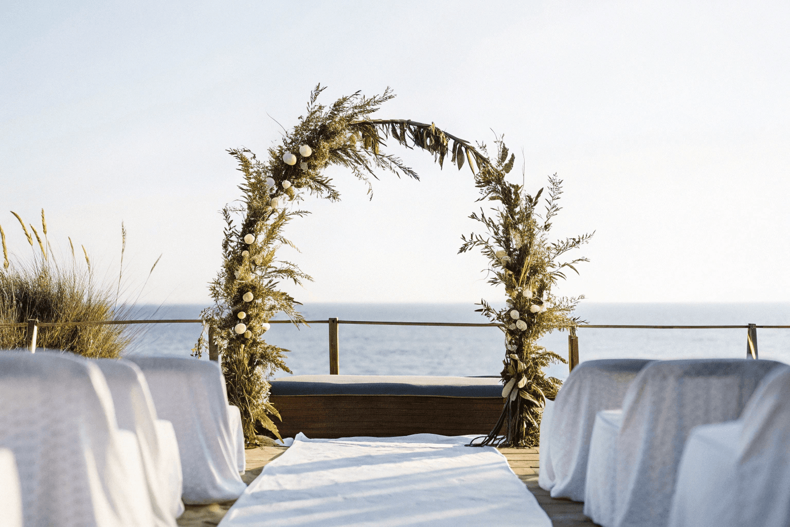 The wedding backdrop is the open sea, shimmering under late afternoon light
