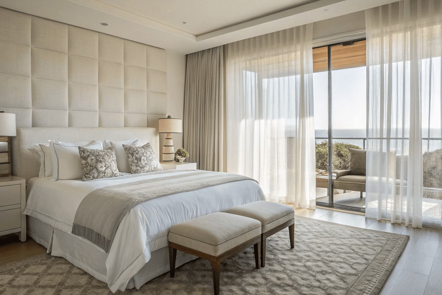 crisp white bedding, layered pillows, a plush bench at the foot of the bed